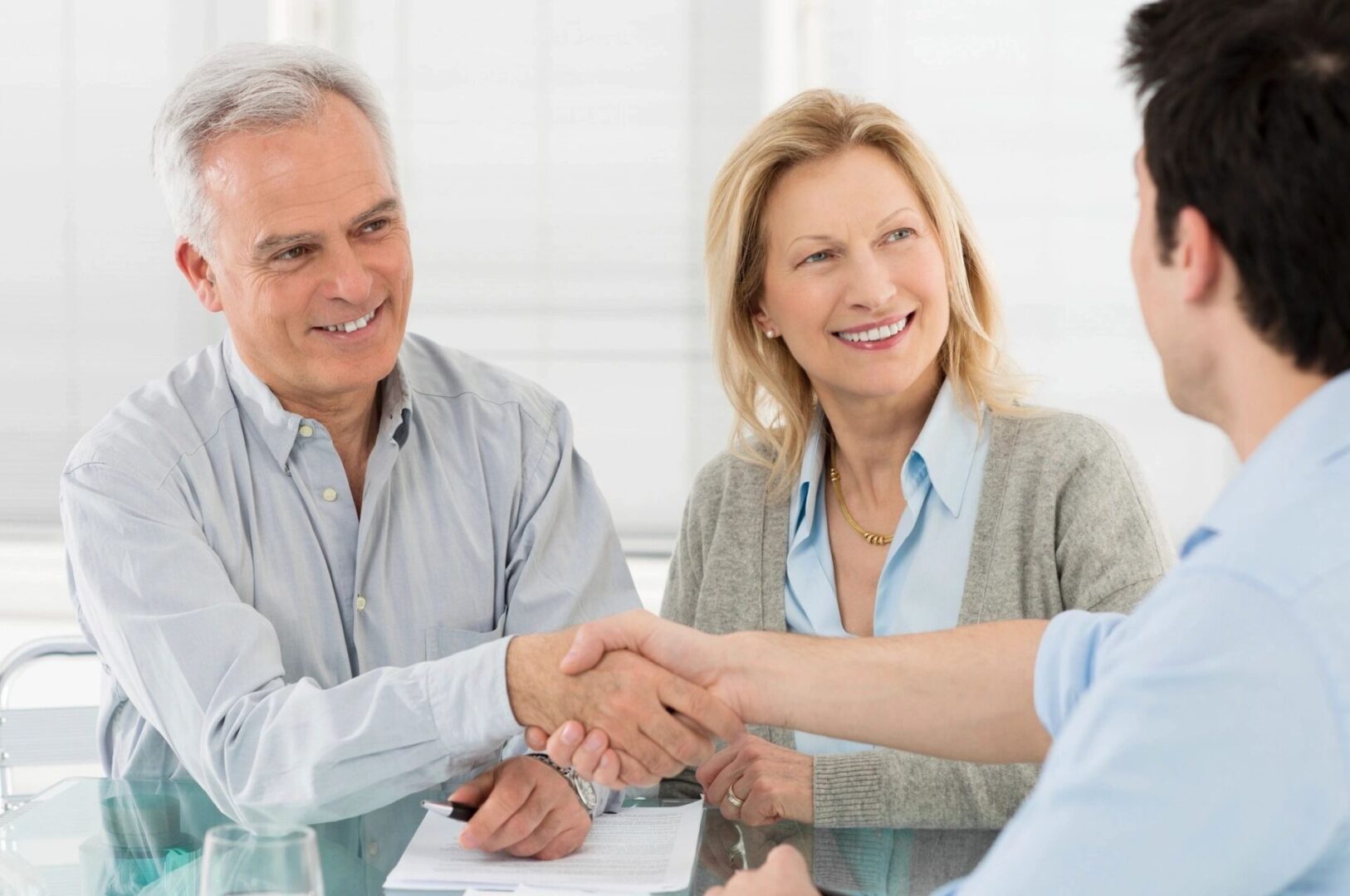 A man and woman shaking hands over papers.