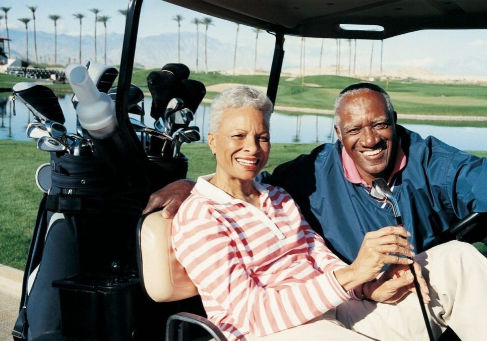 A man and woman sitting in the back of a golf cart.